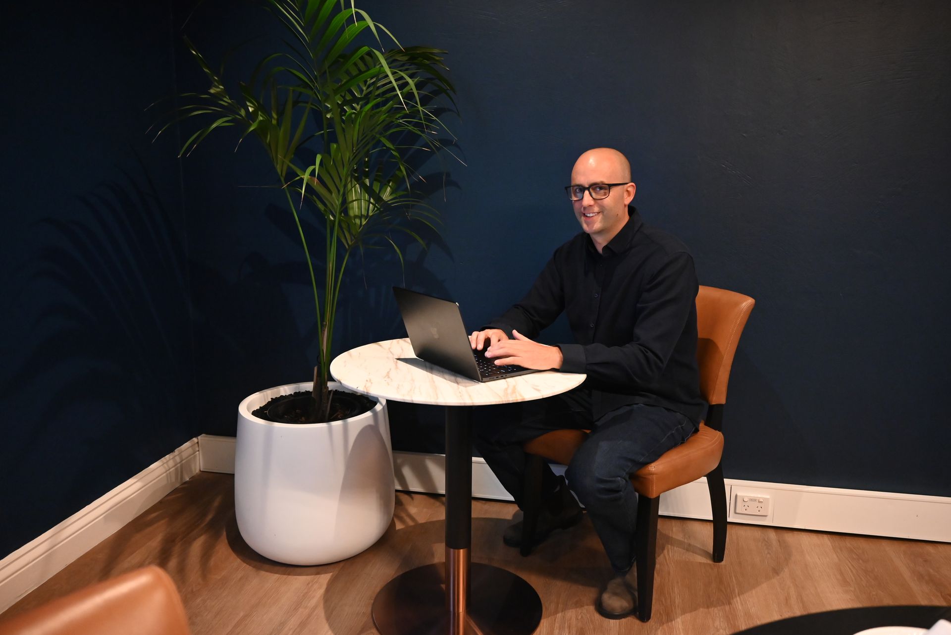 AI consultant Mat Tower working on-site at a laptop, building custom Claude AI administrative workflows and integrations for a local business client in Sydney.