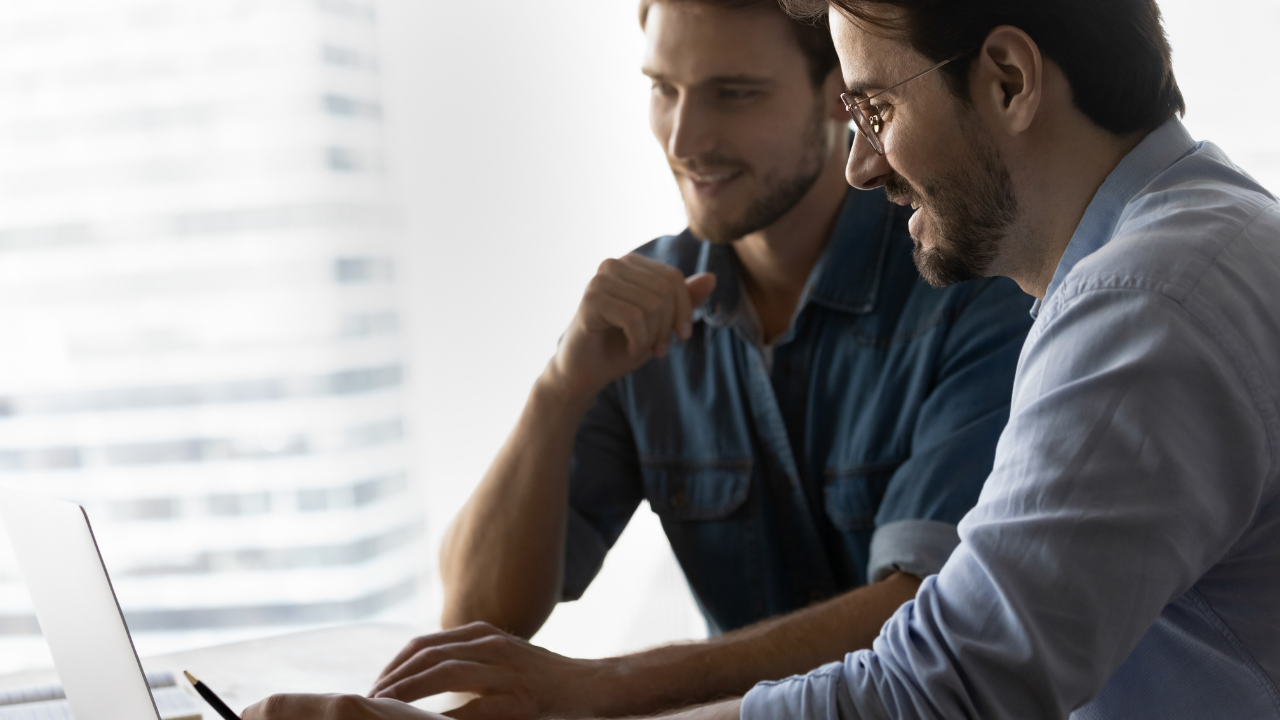 Two colleagues looking at a laptop screen together