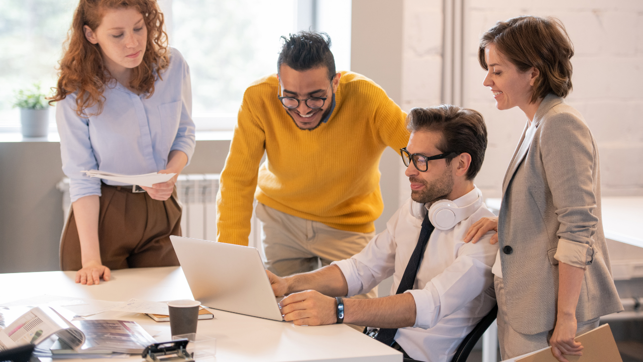 Four colleagues gathered around a laptop in an office
