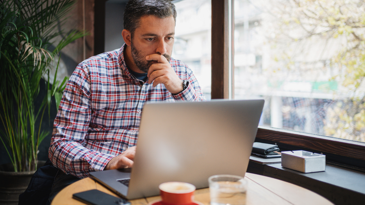 A man working alone at a laptop by a window